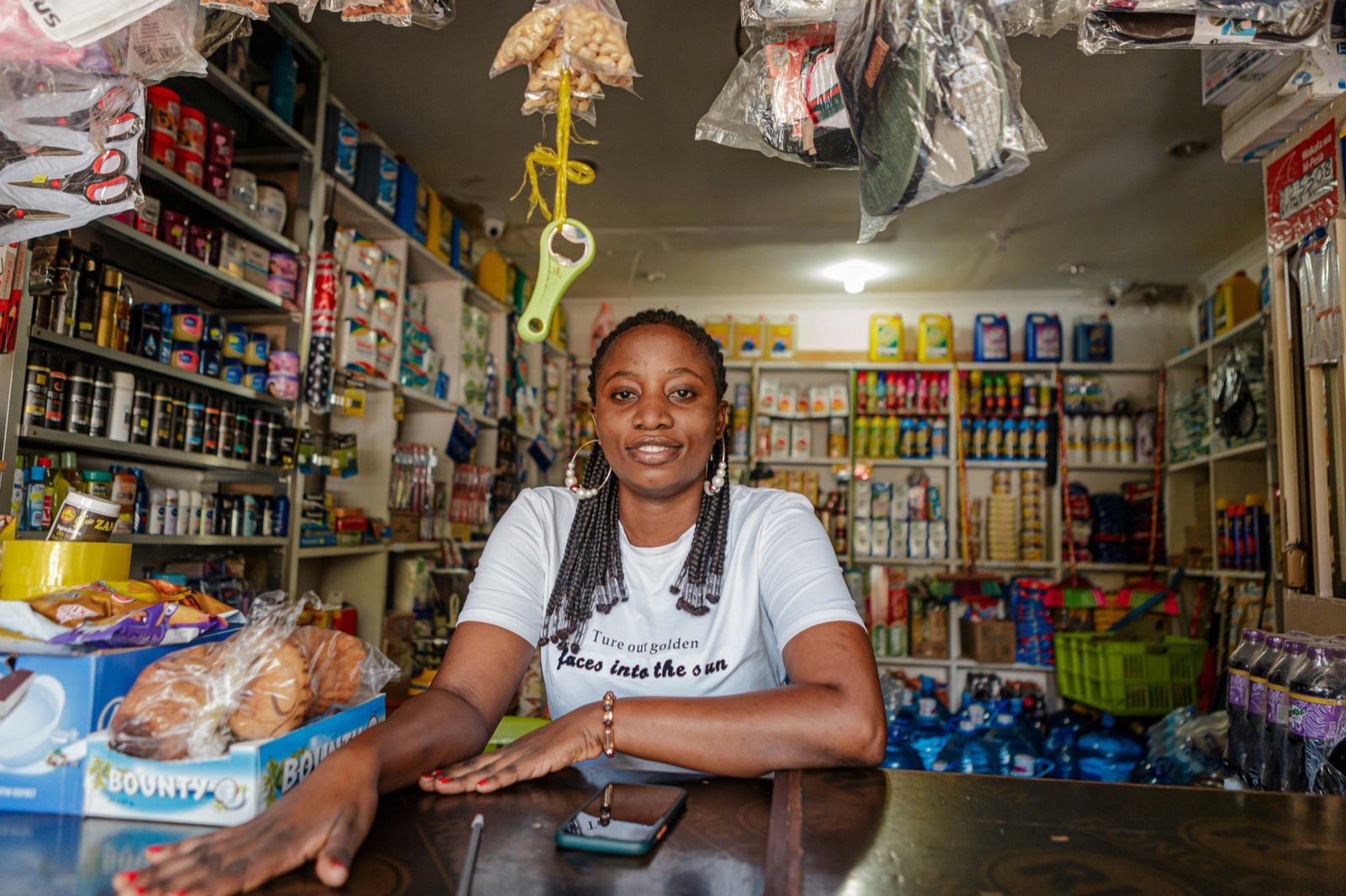 A young shopkeeper standing behind the counter of her well-stocked provisions store.
