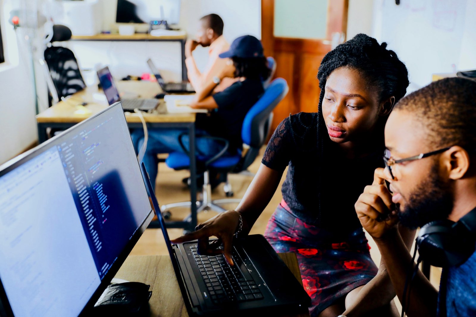 Two colleagues working together at a laptop in a technology workspace.