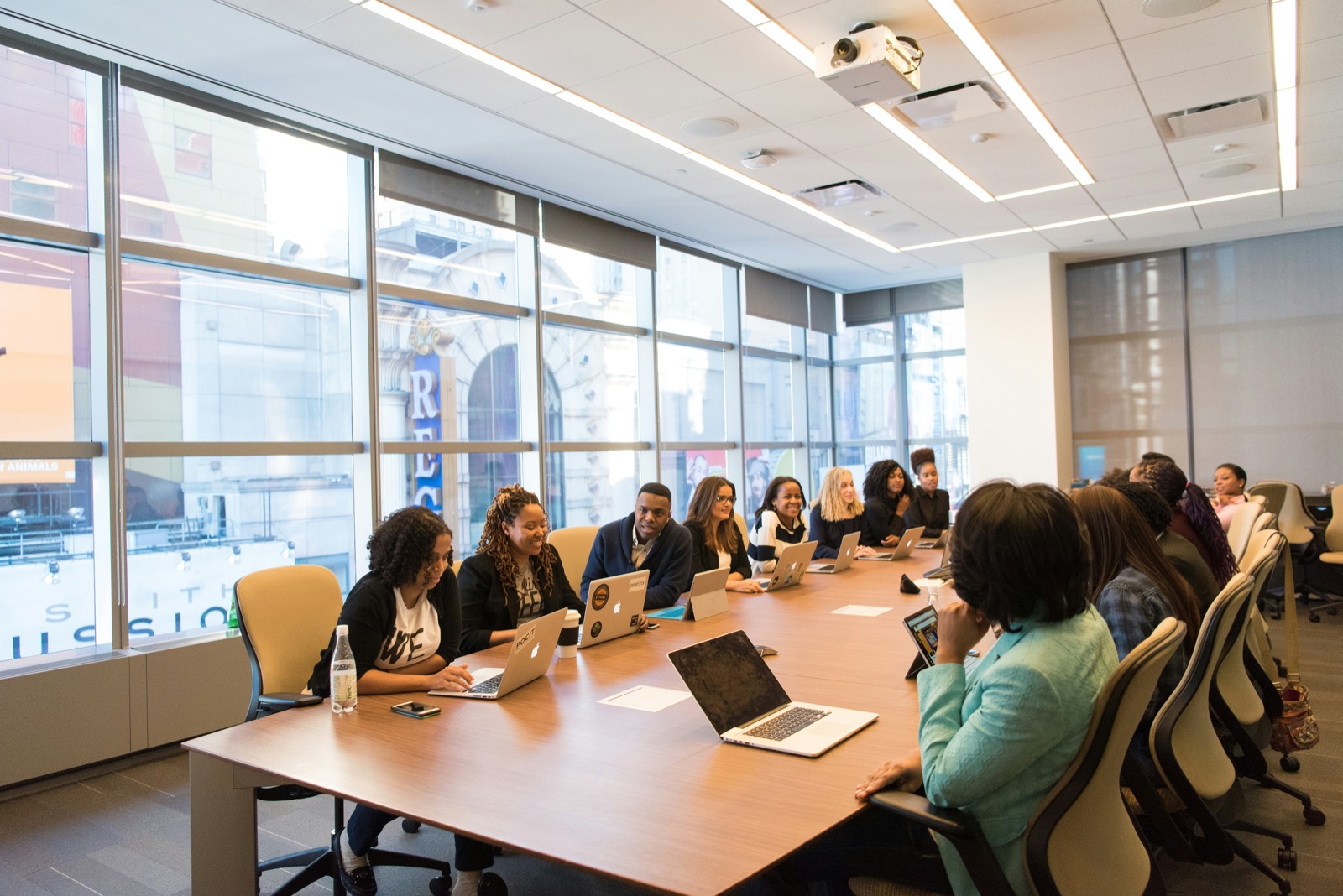 A large boardroom convening, with participants seated around a long conference table.
