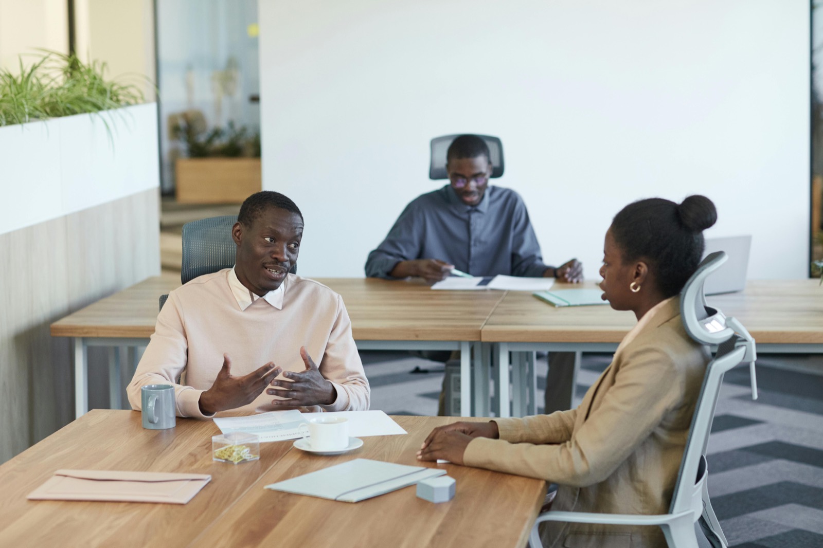 Colleagues in discussion across a table in an open-plan office.