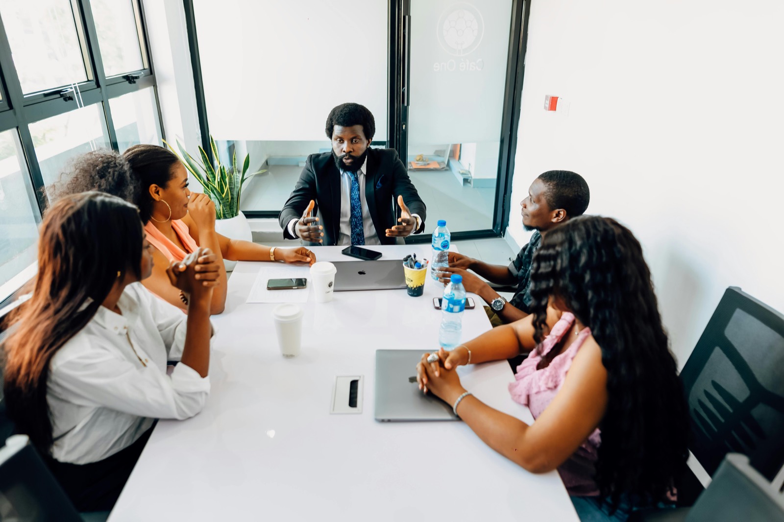 A speaker addressing colleagues seated around a conference table.